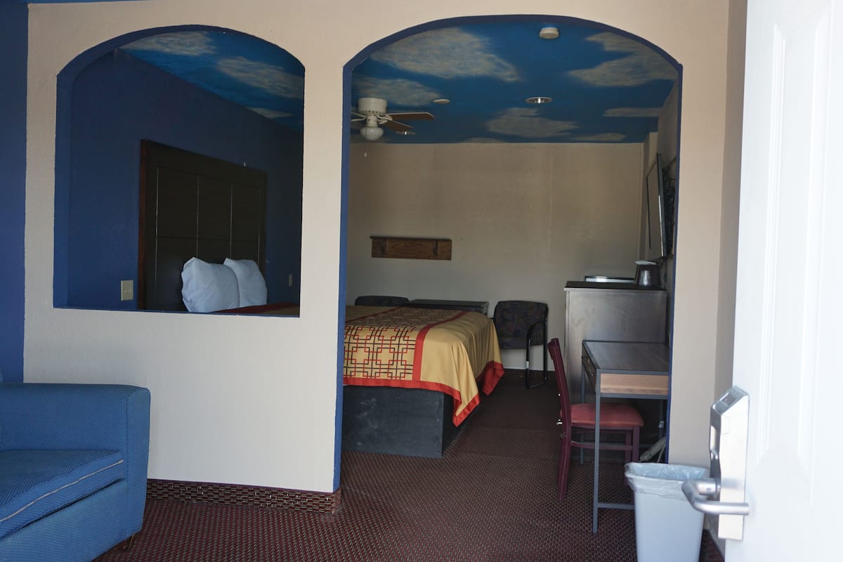 A hotel room with a bed, a desk, a chair, and a blue couch.