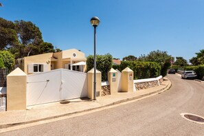 A residential street with a beige house, a white gate, and a lamp post. - Perfect 4 bedroooms Villa in Cala Blanca  (Cala Blanca)