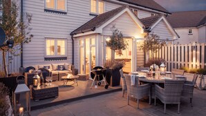 Una casa a due piani con un patio arredato con mobili da esterno e un barbecue.