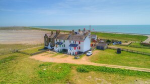 A coastal house with a grassy front yard, a driveway, and a view of the sea. - Coastguards Lookout -  a cottage that sleeps 4 guests  in 2 bedrooms (Jurys Gap)