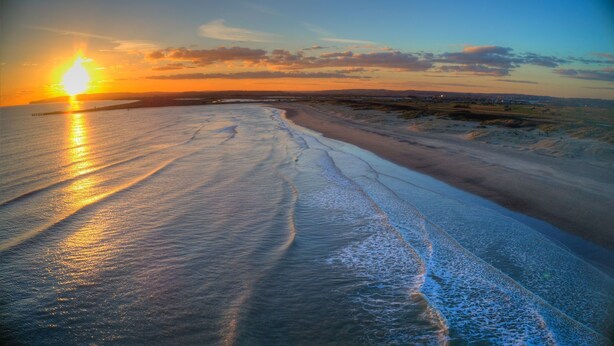 A beach with a sunset, waves, and a distant city skyline. - The Beach House -  a cottage that sleeps 6 guests  in 3 bedrooms (Rye)