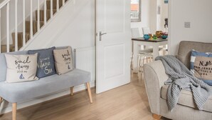 A modern living room with a staircase, a dining area, and a kitchen in the background. - The Beach House -  a cottage that sleeps 6 guests  in 3 bedrooms (Rye)