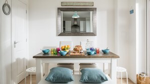Une cuisine lumineuse avec une table en bois, deux coussins bleus et une suspension.