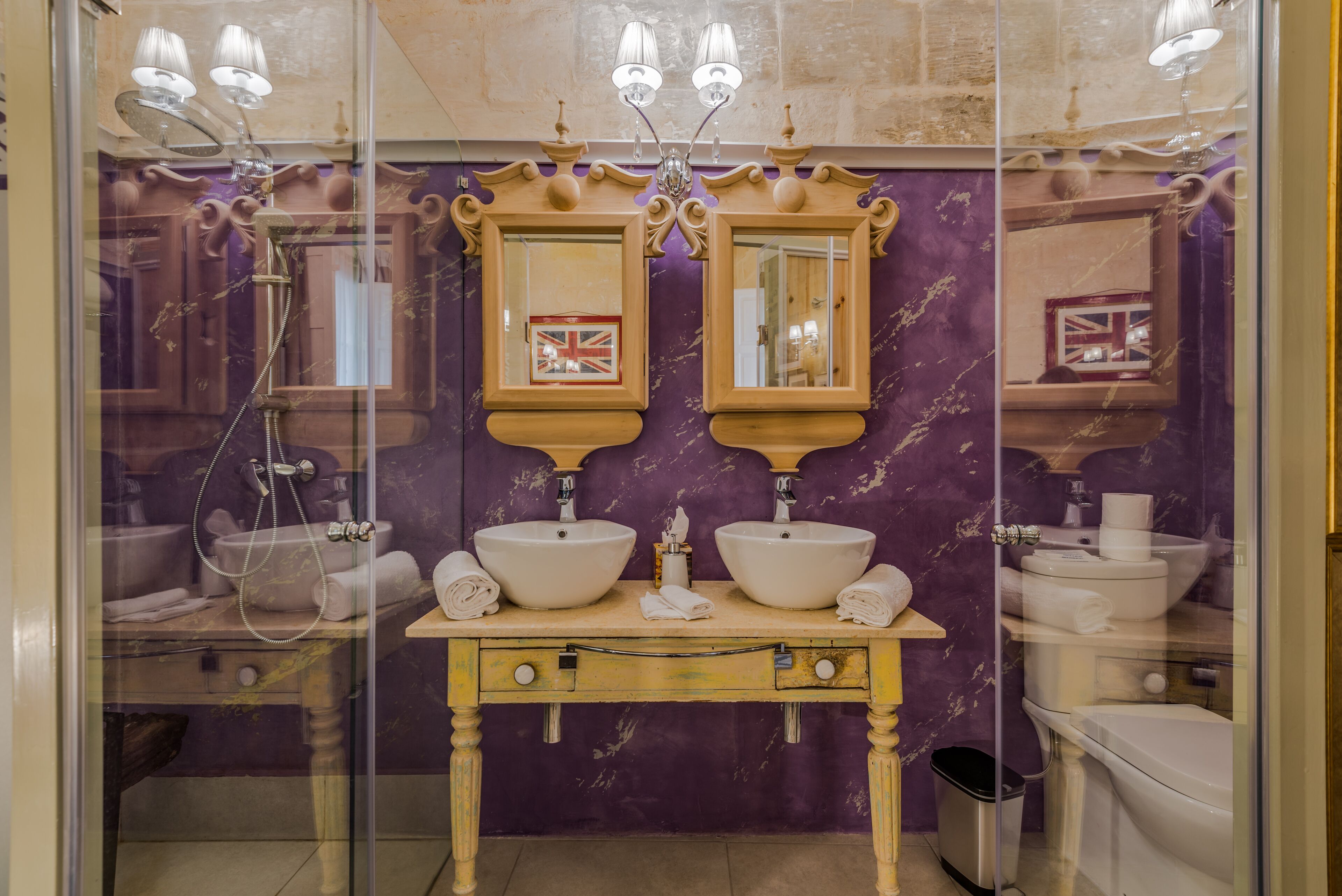 A bathroom with two sinks, a vanity, and a shower.
