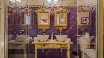 A bathroom with two sinks, a vanity, and a shower.