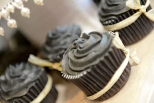 Primer plano de cupcakes de chocolate con cobertura blanca y un lazo encima.