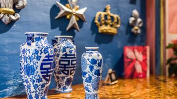 Três vasos azuis e brancos com padrão sobre uma superfície de madeira, com elementos decorativos ao fundo.