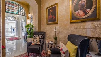 A lobby with a stone wall, a framed portrait, a potted plant, and a sofa with decorative pillows.