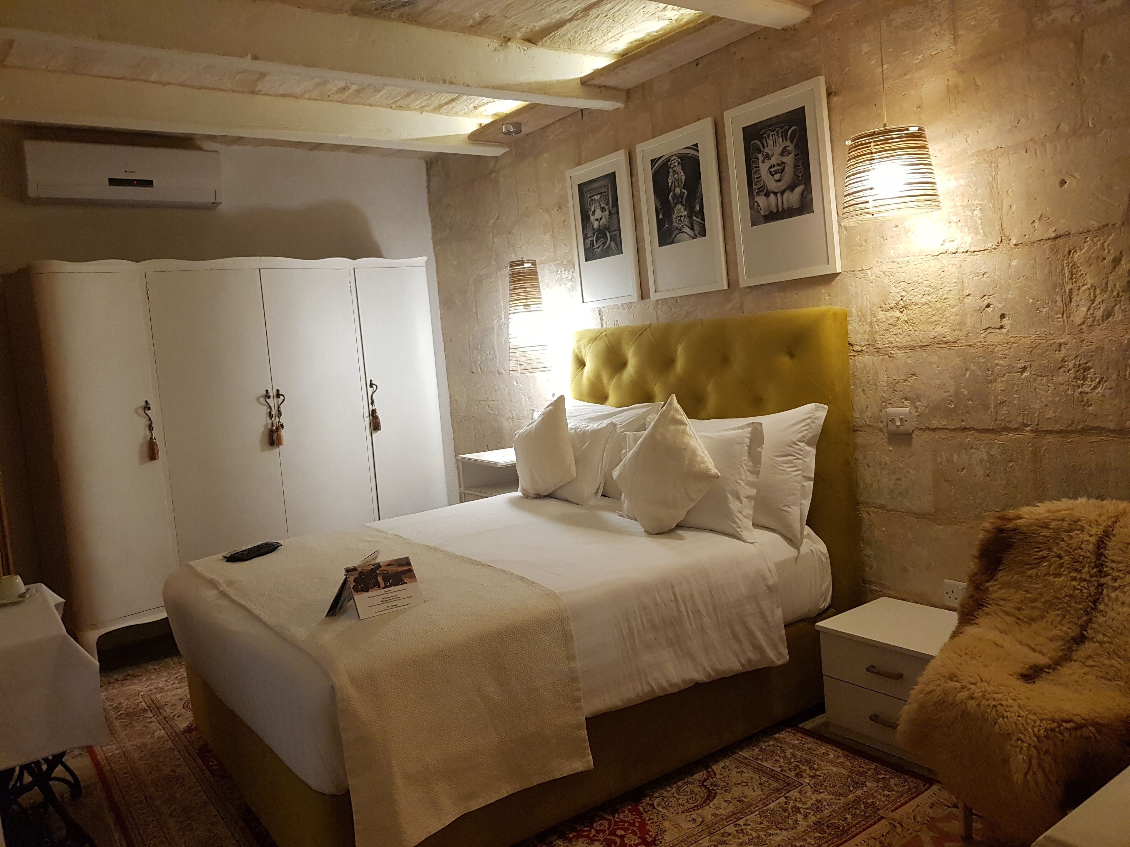 A bedroom with a bed, a wardrobe, a nightstand, and a fluffy chair.