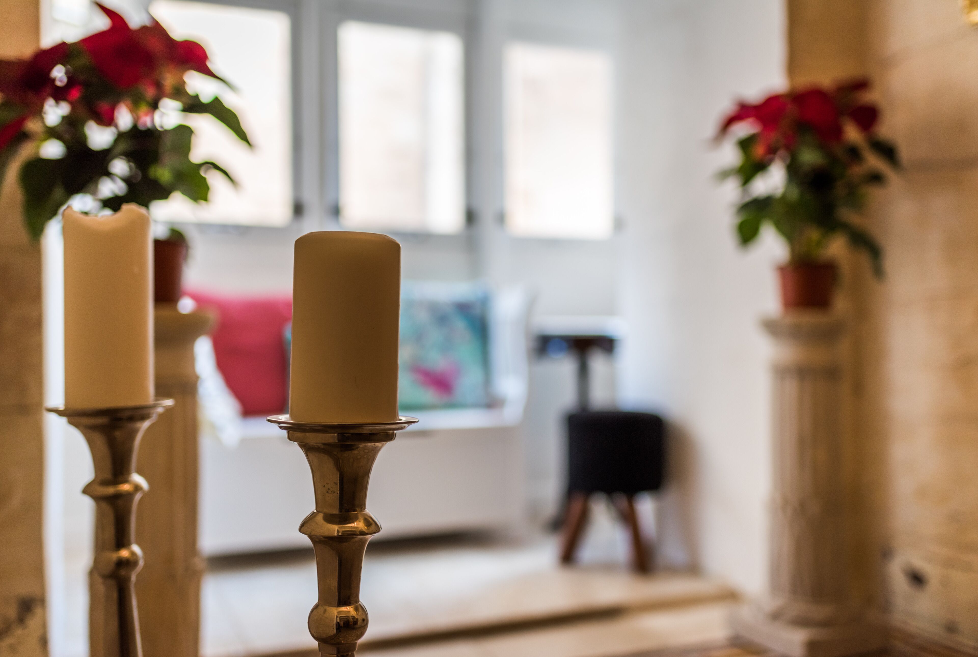 Portavelas con velas en una habitación con ventana y un cuadro en la pared.