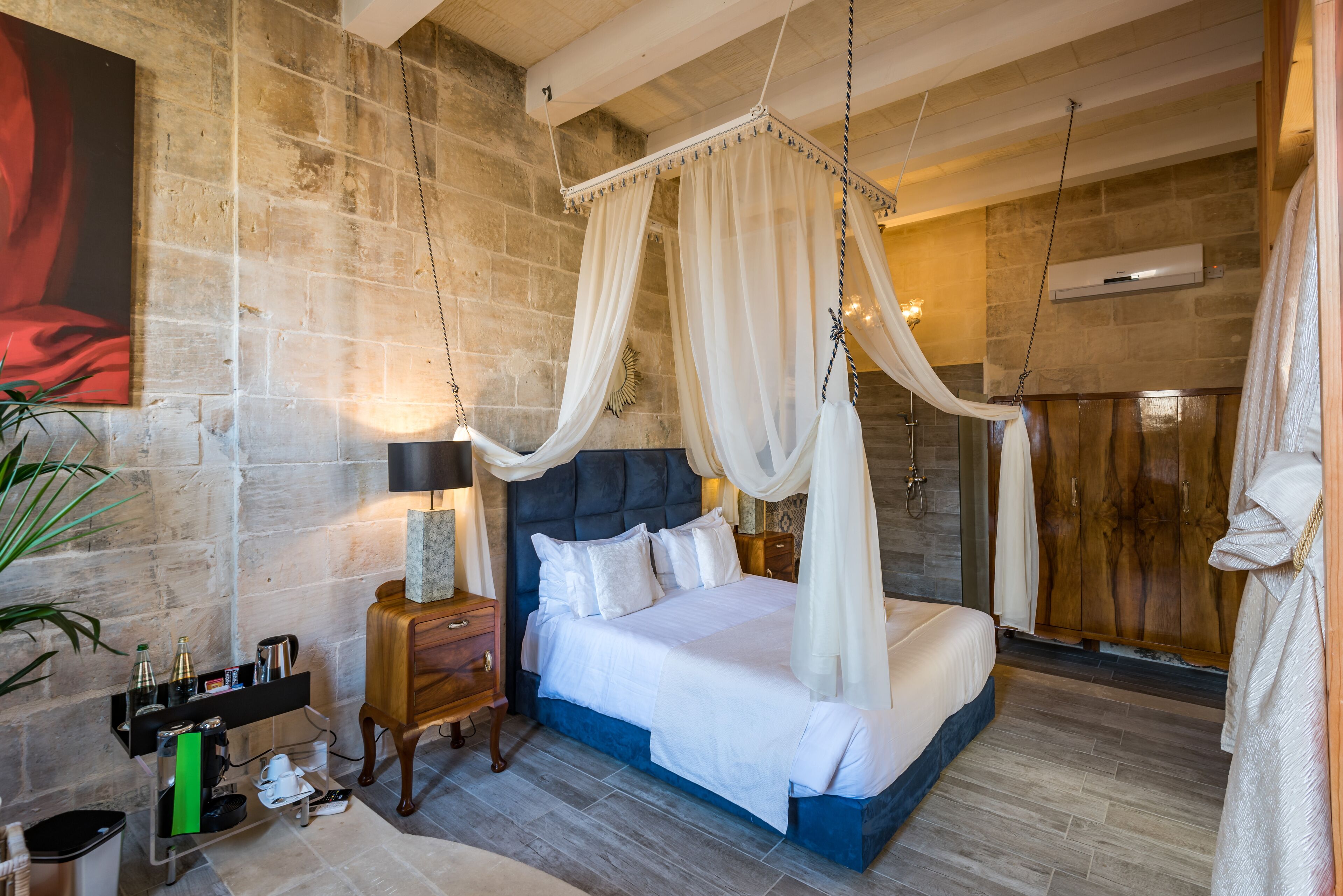 Un dormitorio con cama con dosel, mesita de noche, televisor montado en la pared y armario de madera.