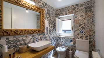A bathroom with a large mirror, a vessel sink, a bidet, and a toilet.