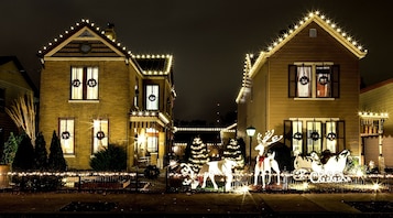 Dos casas adornadas para las fiestas, con coronas y árboles de Navidad.