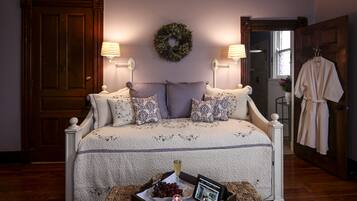 A bedroom with a bed, bedside lamps, a nightstand, a tray with a candle, and a framed photo.