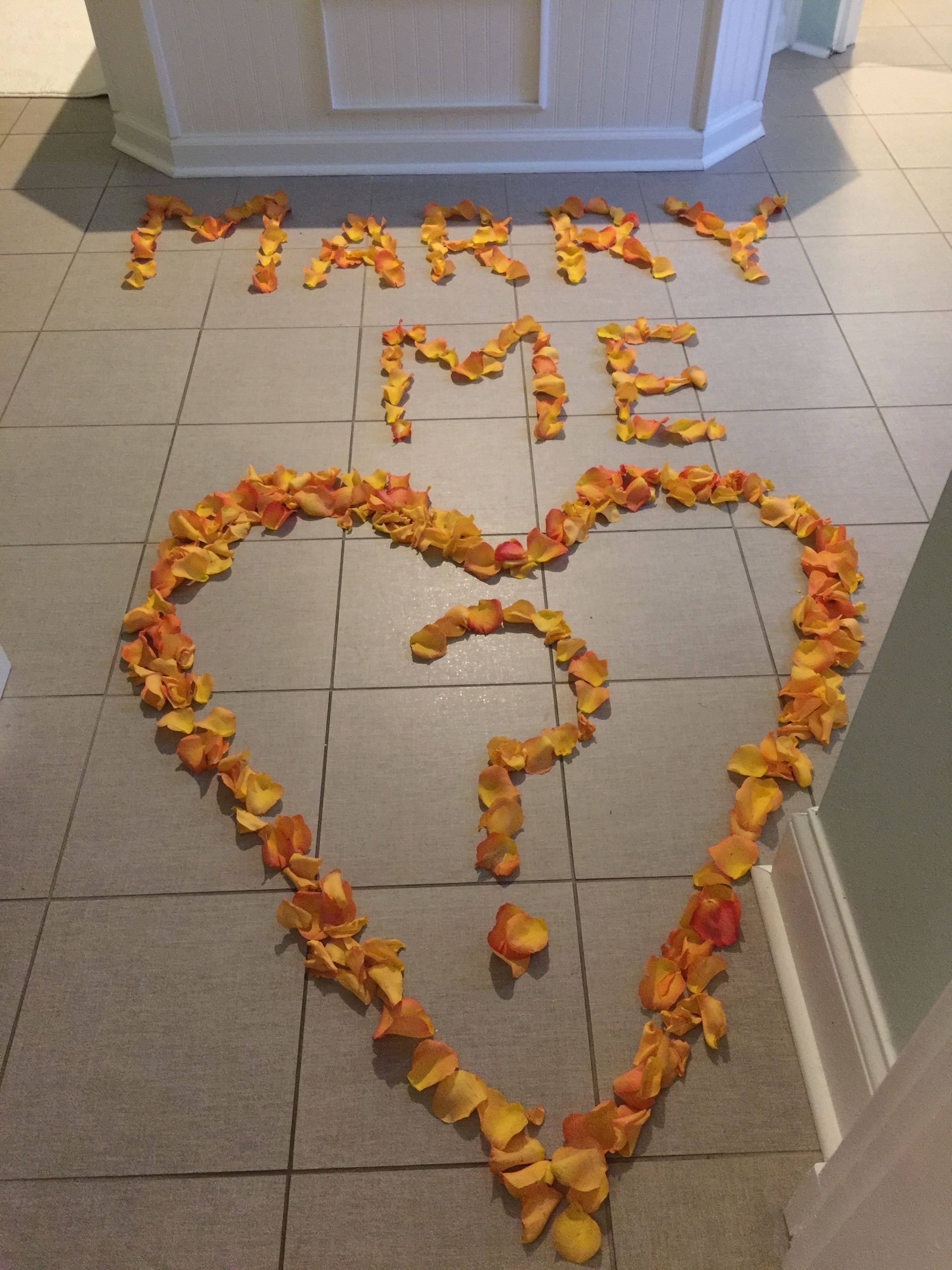 Een hartvormige bloemstuk van rozenblaadjes op een betegelde vloer.
