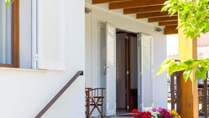 Een trap die leidt naar een houten veranda met een stenen plantenbak vol kleurrijke bloemen.