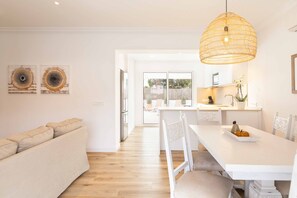 A modern kitchen with white cabinetry, a dining table, and a hanging light fixture. - Berganti - Fantastic villa with pool in Platges de Muro (Muro (Platja de Muro))