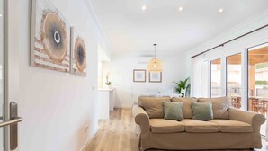 Een moderne woonkamer met een beige bank, een houten vloer en een groot raam.