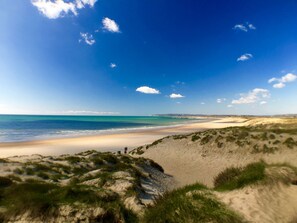 Ein Strand mit blauem Himmel und weiter Küste.