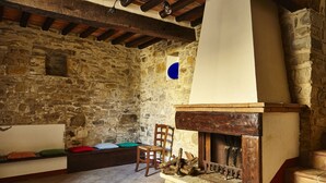 A rustic stone-walled room with a fireplace, wooden beams, and a bench with cushions. - Nice apartment for 2 people with WIFI, pool, TV and pets allowed, close to Arezzo (Capolona)
