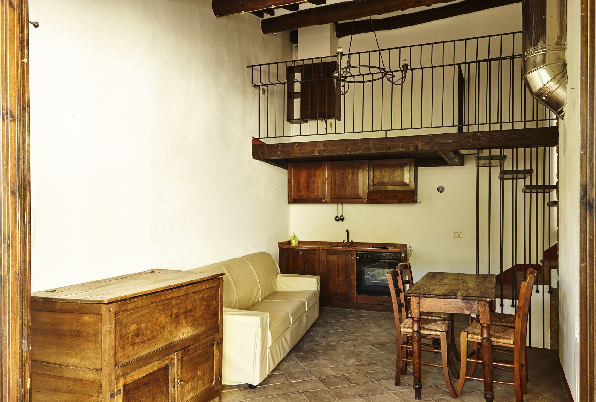 A rustic kitchen with wooden cabinets, a built-in oven, and a dining area with a wooden table and chairs.