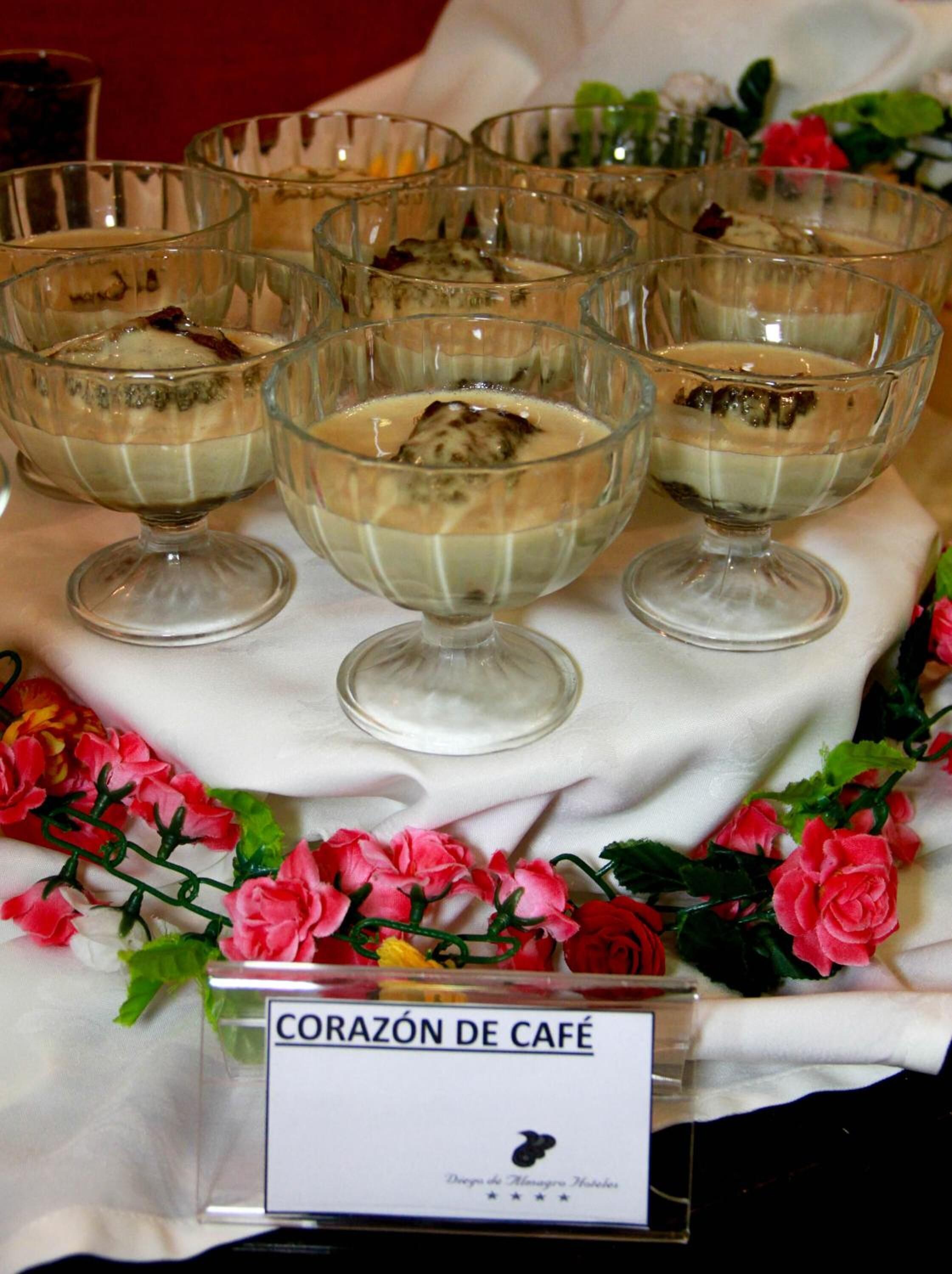 A display of heart-shaped desserts labeled "CORAZÓN DE CAFÉ" on a table with a floral arrangement.