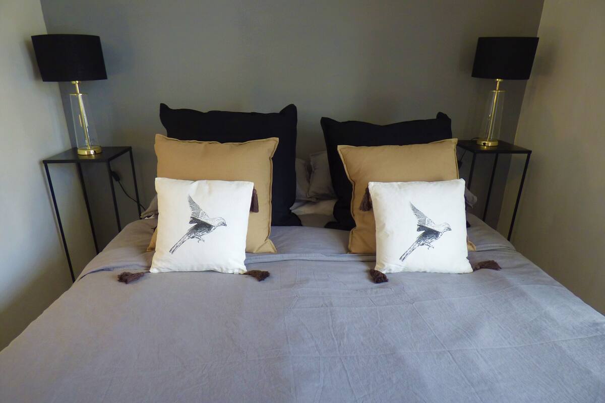 A bed with two pillows, each featuring a bird design, and two bedside lamps on either side.