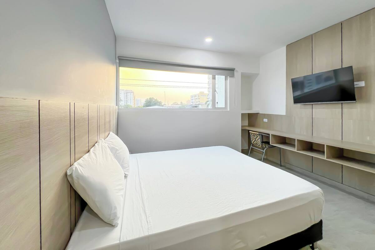 Habitación empresarial | Escritorio, cortinas blackout y tabla de planchar con plancha 