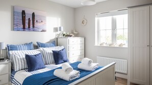 A bedroom with a bed, white dresser, and a window with a view of the sea.