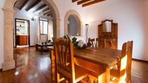 A dining area with wooden furniture, stone arches, and exposed wooden beams.