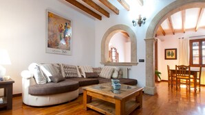 A living room with a wooden floor, a sofa, a coffee table, and an arched doorway.