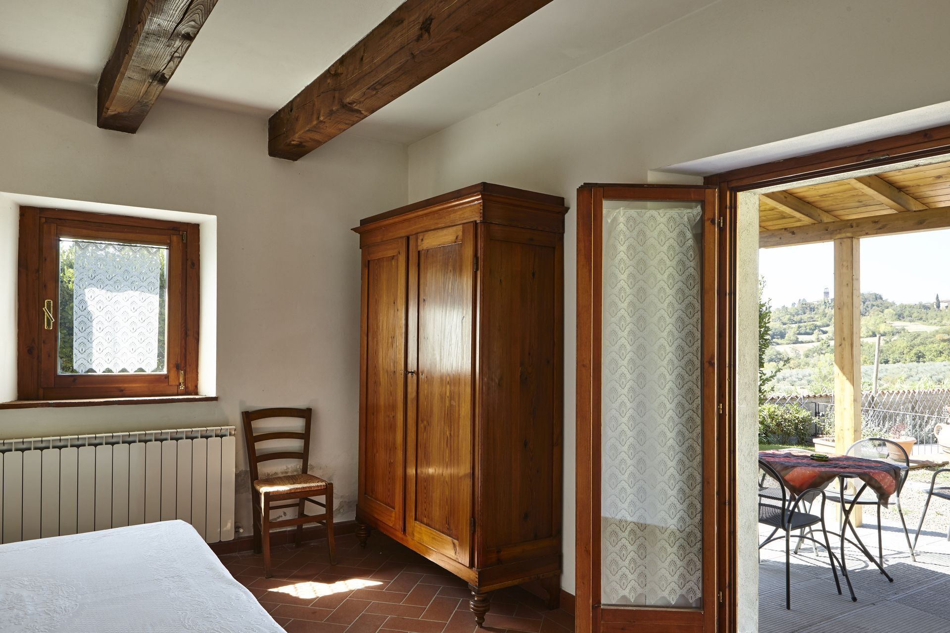 Une chambre avec une armoire en bois, une chaise, un radiateur et une fenêtre à vitres dépolies.