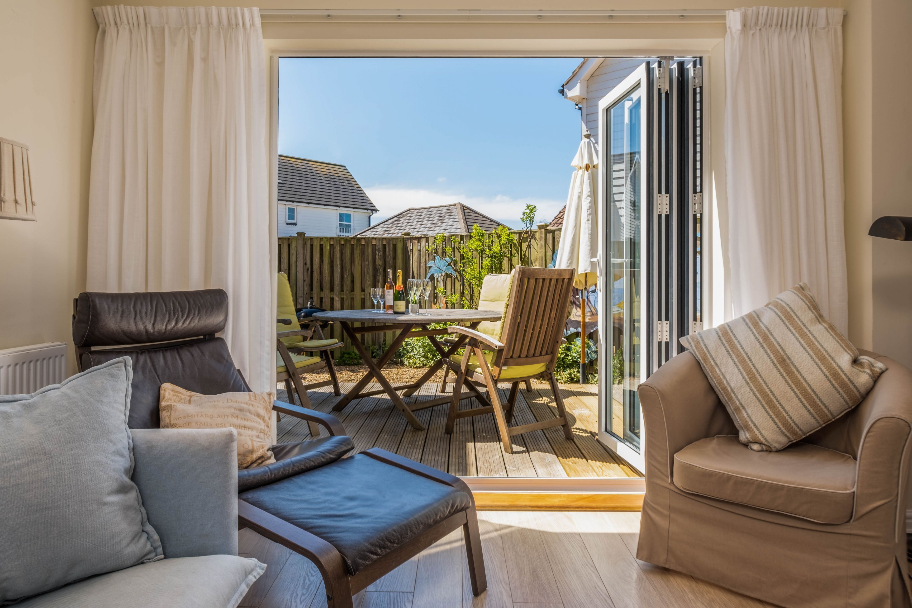A cozy patio area with a wooden table, chairs, and a cushioned sofa.