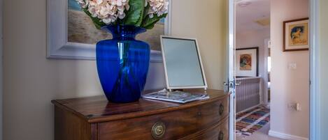 A wooden dresser with a blue vase and a laptop.