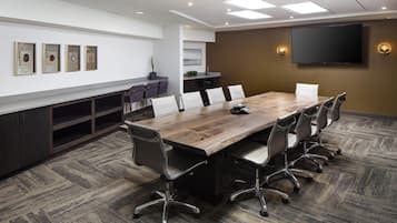 A conference room with a long table, chairs, a TV, and framed artwork on the wall.