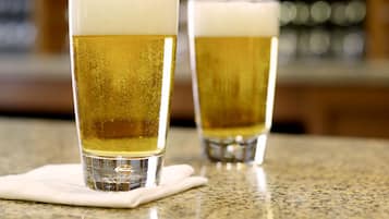 Two glasses of beer on a counter with a blurred background of shelves.