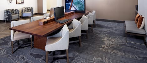 A conference room with a long wooden table, multiple chairs, a large screen, and artwork on the walls.
