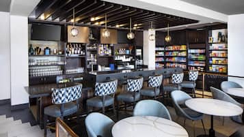 A bar area with seating, shelves of bottles, and a television.