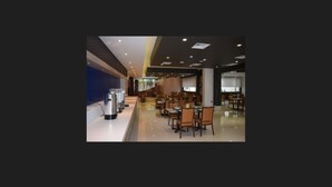 A modern dining area with rows of tables and chairs, a water dispenser, and a blue accent wall.