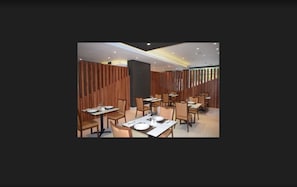 A modern restaurant interior with wooden panel dividers, tables set with white tablecloths, and chairs. - Diego de Almagro Talca Express (Talca)