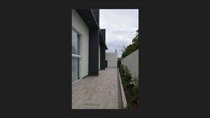 A modern building with a flat roof, large windows, and a paved walkway.