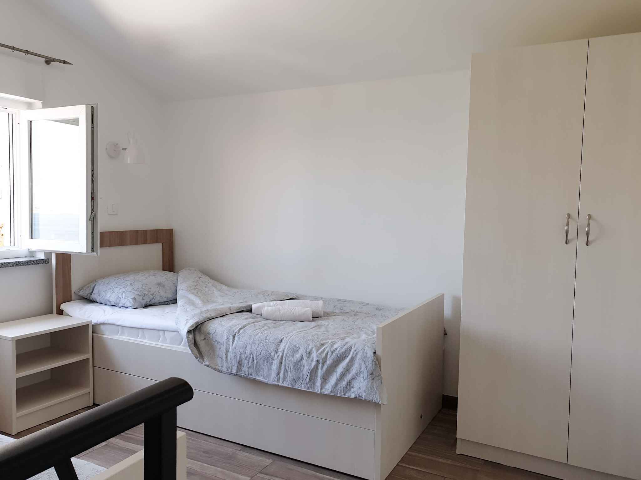 Une chambre à coucher avec un lit, une armoire, un bureau et une fenêtre.