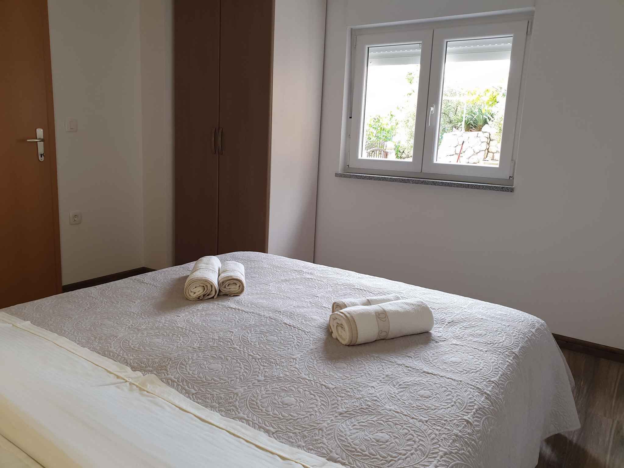 A neatly made bed with a patterned bedspread and two rolled towels on it.