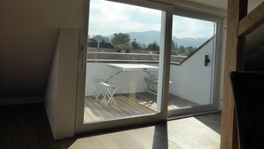 A room with a large sliding glass door leading to an outdoor deck with a table and chairs. - Top modern 2-bedroom penthouse apartment in Bern - Beautiful flat roof in Berne City (Bern)