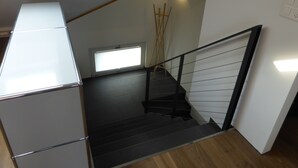 A staircase with a black railing, a wooden floor, and a small window with blinds. - Top modern 2-bedroom penthouse apartment in Bern - Beautiful flat roof in Berne City (Bern)