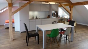 A modern loft with exposed wooden beams, a kitchen with white cabinets, and a dining area with a table and chairs. - Top modern 2-bedroom penthouse apartment in Bern - Beautiful flat roof in Berne City (Bern)