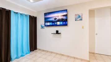Quarto com televisão de tela plana na parede, uma porta e piso revestido de azulejos.