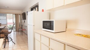 A kitchen with a microwave, a refrigerator, and a dining area with chairs and a table. - Montones Beach Apartment C-3 (Isabela)