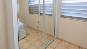 A room with a sliding glass door, a window with blinds, and a tiled floor. - Montones Beach Apartment C-3 (Isabela)