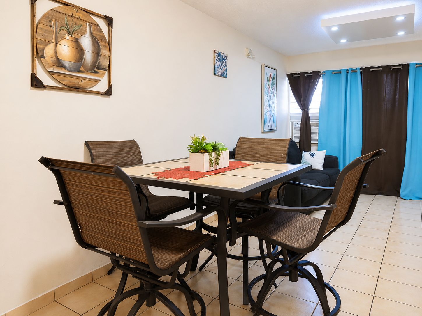 A dining area with a table, chairs, and a potted plant.